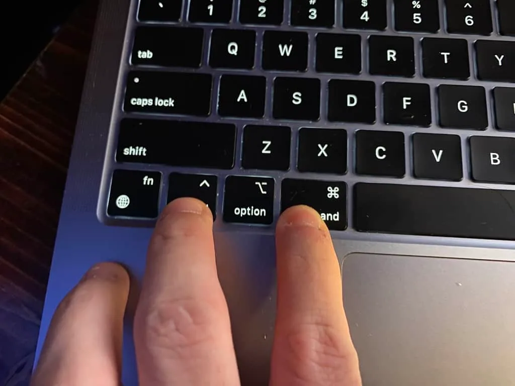 hands on MacBook keyboard pressing power button